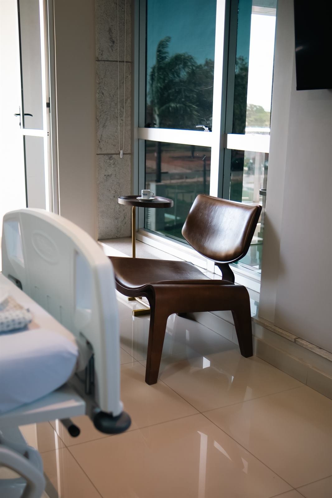 Poltrona de couro junto à janela, com mesa lateral e café
